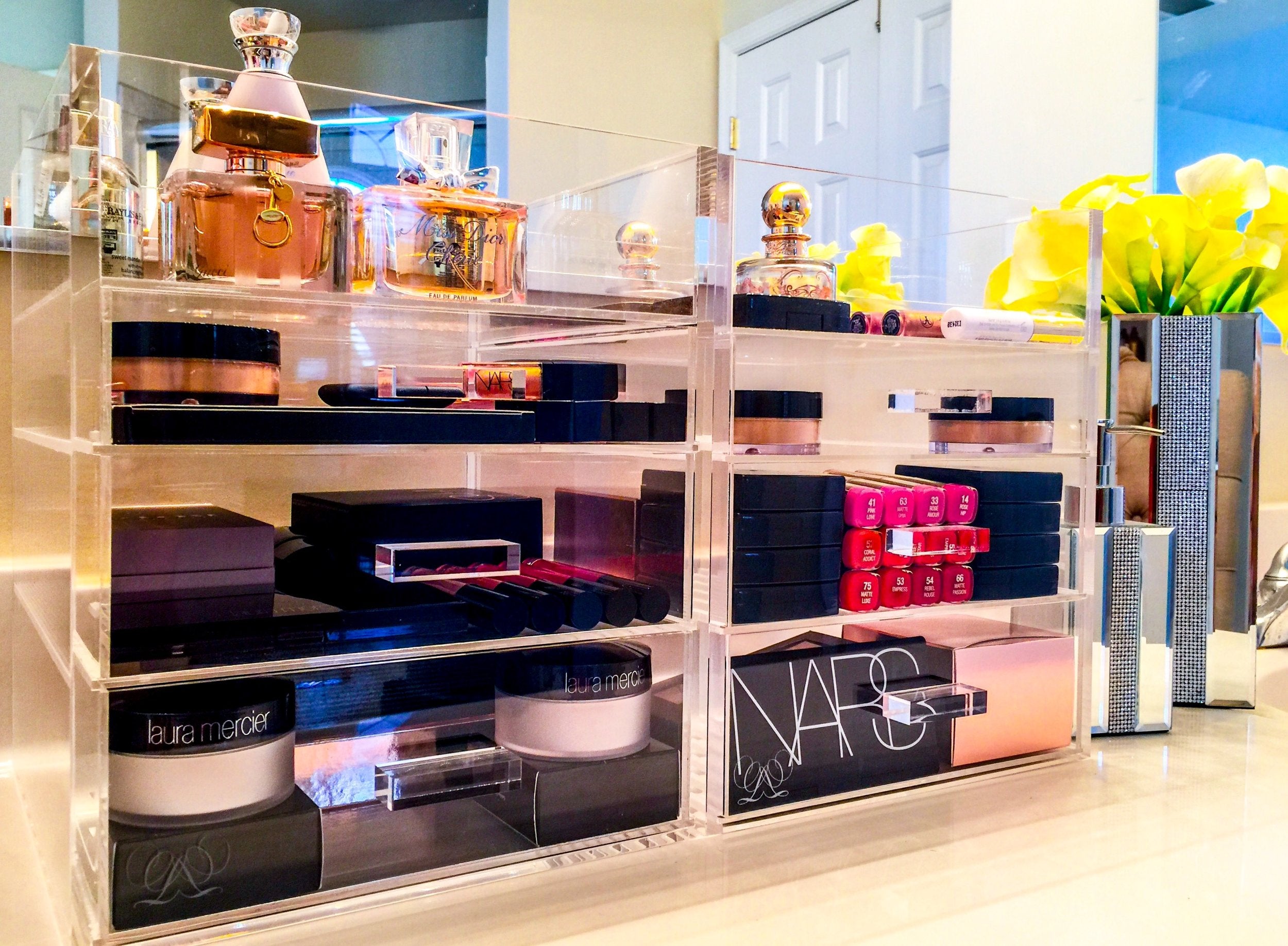 Two large acrylic makeup organizers side by side in a bathroom